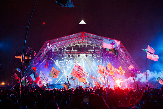 Festival stage at night with flags in the crowd