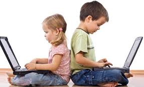 two young children on laptops sitting back to back