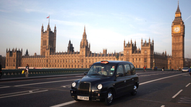 black taxi on bridge in front of houses of parliament